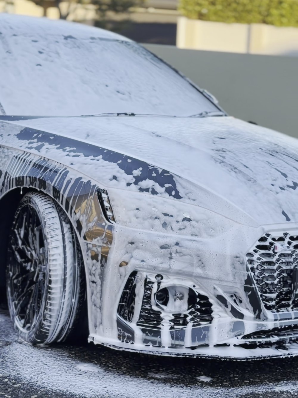 Snow foam pre-wash covering a vehicle before the contact wash